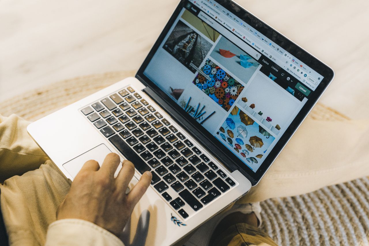 Une personne utilise un ordinateur portable pour parcourir des sites de photos stock. Un travail de freelance dans un cadre cosy.